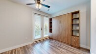 Located at 484 Lazelle Rd in Columbus, OH, this thoughtfully designed studio unit makes excellent use of its compact footprint across a single floor. The open-concept kitchen and living area serves as the heart of the space, anchored by a large marble-style quartz peninsula with a stainless steel sink and stylish pendant lighting above. The kitchen is equipped with stainless steel appliances — including a refrigerator, electric range, and over-the-range microwave — complemented by white shaker cabinetry and a classic subway tile backsplash. Wood-look flooring runs throughout, adding warmth and visual continuity. The living area is brightened by a ceiling fan and a full-length glass balcony door that invites natural light and provides access to an outdoor balcony with green views. A built-in wall unit featuring a Murphy bed flanked by open shelving and storage cabinets maximizes functionality without sacrificing style. The bathroom is finished with a white vanity topped with marble-look counters, black hardware accents, and wood-look tile flooring. Additional conveniences include two closets, a pantry, and an in-unit laundry area, making this studio a complete and efficient living space.