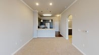 This single-floor residence offers a thoughtfully designed layout with a seamless blend of contemporary finishes and functional living spaces. The kitchen serves as a focal point, showcasing gray shaker-style cabinetry, quartz countertops with elegant veining, and a tile backsplash in a subtle geometric pattern. Stainless steel appliances, including a refrigerator with ice dispenser, electric range, and over-the-range microwave, complete the space. A peninsula with an undermount sink and pendant lighting above connects the kitchen to the open living area, which is defined by crown molding and a graceful arched entryway.

The living area features plush carpeting and recessed lighting, creating a comfortable and inviting atmosphere. Multiple bedrooms continue the carpeted flooring, each equipped with ceiling fans and windows fitted with blinds that allow natural light to filter in. One bedroom includes a walk-in closet and direct access to an adjoining bathroom.

The bathroom is finished with marble-style countertops and a full tub-shower combination with built-in shelving. A dedicated laundry room provides in-unit convenience, housing a full-size washer and dryer with wire shelving above. Throughout the space, neutral tones and clean lines contribute to a cohesive, modern aesthetic.