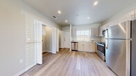 This well-appointed two-floor residence showcases a clean, modern aesthetic with thoughtful finishes throughout. The kitchen is a functional centerpiece, featuring a full suite of stainless steel appliances — including a range, microwave, dishwasher, and refrigerator — paired with light gray cabinetry and striking granite countertops. Recessed lighting and a window above the sink keep the space bright and airy, while light wood-look flooring extends across the main living areas.

The living and dining areas provide generous, open space bathed in natural light from large windows fitted with horizontal blinds. A ceiling fan with a light fixture adds comfort and character to the carpeted upper-level rooms, one of which features a door leading to a private balcony with neighborhood views.

The bedrooms are carpeted for warmth and comfort, each offering louvered closet doors for storage. The bathrooms continue the refined aesthetic of the home, boasting wide granite-topped vanities with undermount sinks, large mirrors, and wood-look tile flooring. Throughout the residence, neutral tones in soft beige and gray create a cohesive, calming atmosphere well-suited to modern living.