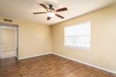 Located on N Hills St in Meridian, Mississippi, this single-floor residence offers a practical and comfortable layout across several well-defined living spaces. The main living area features rich, dark hardwood-style flooring and a ceiling fan with a light fixture, creating a welcoming and functional common space. An open pass-through connects the living area to the kitchen, which is equipped with white cabinetry, light-toned countertops, a double-basin sink, and black appliances including an electric range and over-the-range microwave — all set above matching hardwood-style flooring.

The bedrooms vary in their finishes and character. One bedroom showcases the same hardwood-style flooring with a ceiling fan and a window fitted with blinds for natural light control. Another bedroom features plush carpeting, a ceiling fan, a window with blinds, and a sliding closet for added storage. A third carpeted bedroom also includes a ceiling fan and window with blinds. Textured ceilings are consistent throughout the home, adding a classic residential feel.

The bathroom is clean and straightforward, featuring a full tub-and-shower combination with white tile surround and chrome fixtures. Warm neutral wall tones flow throughout the entire residence, tying each space together into a cohesive and move-in-ready home.