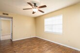 Located on N Hills St in Meridian, Mississippi, this single-floor residence offers a practical and comfortable layout across several well-defined living spaces. The main living area features rich, dark hardwood-style flooring and a ceiling fan with a light fixture, creating a welcoming and functional common space. An open pass-through connects the living area to the kitchen, which is equipped with white cabinetry, light-toned countertops, a double-basin sink, and black appliances including an electric range and over-the-range microwave — all set above matching hardwood-style flooring.

The bedrooms vary in their finishes and character. One bedroom showcases the same hardwood-style flooring with a ceiling fan and a window fitted with blinds for natural light control. Another bedroom features plush carpeting, a ceiling fan, a window with blinds, and a sliding closet for added storage. A third carpeted bedroom also includes a ceiling fan and window with blinds. Textured ceilings are consistent throughout the home, adding a classic residential feel.

The bathroom is clean and straightforward, featuring a full tub-and-shower combination with white tile surround and chrome fixtures. Warm neutral wall tones flow throughout the entire residence, tying each space together into a cohesive and move-in-ready home.