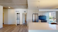 Located in Chicago's vibrant Old Town neighborhood, this modern single-floor residence at 1353 N Sedgwick St offers a thoughtfully designed open-concept layout with contemporary finishes throughout. The living area is expansive and bright, featuring light wood-tone flooring and striking exposed concrete ceilings that lend an industrial character to the space. Large floor-to-ceiling windows and a sliding glass door flood the living area with natural light while framing views of the surrounding Chicago cityscape.

The kitchen is seamlessly integrated into the living space via a sleek, white waterfall-edge island with an undermount sink. White flat-panel cabinetry extends to the ceiling, complemented by a bold blue-gray backsplash and stainless steel appliances, including a gas range with a range hood and a full-size refrigerator.

The bedrooms continue the clean, minimalist aesthetic with wood flooring and recessed lighting set within the exposed concrete ceilings. Both bathrooms are finished with large-format dark tile flooring, floating white vanities, white quartz countertops, backlit mirrors, and accessibility grab bars. A dedicated in-unit laundry closet with a stacked washer and dryer adds everyday convenience to this well-appointed urban residence.