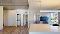 Located in Chicago's vibrant Old Town neighborhood, this modern single-floor residence at 1353 N Sedgwick St offers a thoughtfully designed open-concept layout with contemporary finishes throughout. The living area is expansive and bright, featuring light wood-tone flooring and striking exposed concrete ceilings that lend an industrial character to the space. Large floor-to-ceiling windows and a sliding glass door flood the living area with natural light while framing views of the surrounding Chicago cityscape.

The kitchen is seamlessly integrated into the living space via a sleek, white waterfall-edge island with an undermount sink. White flat-panel cabinetry extends to the ceiling, complemented by a bold blue-gray backsplash and stainless steel appliances, including a gas range with a range hood and a full-size refrigerator.

The bedrooms continue the clean, minimalist aesthetic with wood flooring and recessed lighting set within the exposed concrete ceilings. Both bathrooms are finished with large-format dark tile flooring, floating white vanities, white quartz countertops, backlit mirrors, and accessibility grab bars. A dedicated in-unit laundry closet with a stacked washer and dryer adds everyday convenience to this well-appointed urban residence.