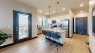 Located at 17675 Welch Plaza in Omaha, Nebraska, this single-floor unit offers a thoughtfully designed layout with modern finishes throughout. The kitchen serves as a functional centerpiece, featuring white shaker cabinetry, stainless steel appliances, a large island with seating for three, pendant lighting, and light wood-style flooring that extends into the main living areas. Natural light flows in through generously sized windows, offering views of the surrounding cityscape.

The living area provides a comfortable, open setting with a large window framing outdoor views, creating a bright and welcoming atmosphere. The well-proportioned hallway connects the private areas of the unit, finished with wood-look tile flooring, recessed lighting, and contemporary dark-trimmed panel doors that lend a cohesive, modern aesthetic.

Two bedrooms offer carpeted floors and windows with outdoor views, with ceiling fans providing added comfort. Both bathrooms are finished with light tile flooring, white vanity cabinetry, and clean, functional layouts — one featuring a shower/tub combination. The overall design balances practicality with contemporary style, making this a well-equipped and visually cohesive living space in west Omaha.