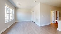 Located at 104 Washington St in downtown Dover, New Hampshire, this thoughtfully designed unit offers a clean, modern aesthetic throughout its efficiently arranged single-floor layout. Light wood-tone flooring flows seamlessly across the entire space, complementing the neutral, warm-white walls and crisp white trim.

The open-concept kitchen and living area serves as the heart of the unit. The kitchen is outfitted with stainless steel appliances — including a refrigerator, range, microwave, and dishwasher — paired with two-tone cabinetry featuring white upper cabinets and charcoal lower cabinets. A white quartz peninsula with an undermount sink and stylish pendant lighting anchors the space. The living area is bathed in natural light from large windows and a sliding glass door that opens to a private balcony overlooking the streetscape.

The bathroom is finished in a bright, contemporary style with a white vanity, built-in open shelving, a large mirror, and a glass-enclosed walk-in shower. A dedicated laundry room provides added convenience, housing a full-size stacked washer and dryer alongside wire shelving for additional storage. This unit offers a polished, move-in-ready living experience in a prime downtown location.