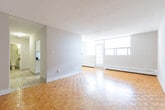 Located at 1431 Lakeshore Rd in Burlington, Ontario, this one-bedroom, one-bathroom unit offers a functional and well-laid-out living space. Warm parquet hardwood flooring flows throughout the living room and bedroom, adding a classic character to the interior. The living room is a bright and open area, benefiting from large windows and a glass-paneled door that floods the space with natural light and provides access to a balcony. Baseboard heating runs along the exterior walls, ensuring year-round comfort. The galley-style kitchen is efficiently designed with white cabinetry, subway tile backsplash, a double basin sink with dark countertops, and a stainless steel refrigerator, with light tile flooring underfoot. The bedroom is a comfortable and well-proportioned retreat, featuring a window with a roller blind, baseboard heating, and the same warm parquet flooring as the rest of the unit. The bathroom is neatly appointed with tile flooring, a white vanity with a dark stone-style countertop, a mirrored medicine cabinet, and wall-mounted lighting. The overall palette is neutral and clean, creating a bright and cohesive ambiance throughout the unit.