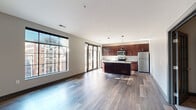 Located in the heart of downtown Columbus at 205 S High St, this two-bedroom, three-bathroom residence offers a well-designed single-floor layout. The open-concept living and kitchen area is anchored by wide-plank hardwood flooring and floor-to-ceiling windows that frame striking views of the surrounding Columbus cityscape, flooding the space with natural light. A sliding glass door provides access to an outdoor area, further enhancing the connection to the vibrant urban surroundings.

The kitchen is a standout feature, equipped with rich dark-wood cabinetry, granite countertops, a central island with pendant lighting overhead, and a full suite of stainless steel appliances including a range, microwave, and refrigerator. A tiled backsplash adds a clean, polished finish.

Both bedrooms are carpeted and finished in neutral tones with dark-trimmed doors, offering a calm retreat. Each bedroom is served by a dedicated closet, including a walk-in closet with wire shelving systems for organized storage. The primary bedroom is a comfortable size, while the second bedroom also provides ample room.

The three bathrooms include clean, modern finishes — one features white subway tile surrounding a soaking tub, a white vanity with chrome hardware, and tile flooring. The layout also includes a hallway connecting all areas efficiently, rounding out this thoughtfully designed urban residence.