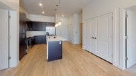 This well-appointed single-floor unit showcases a clean, modern aesthetic with a thoughtful layout designed for comfortable living. The open-concept kitchen serves as the heart of the space, featuring dark espresso cabinetry, stainless steel appliances including a refrigerator, microwave, and range, and a central island with a light quartz countertop and undermount sink. Pendant lighting adds a stylish touch above the island, while light wood-look flooring extends throughout the main living areas, contributing to a bright and cohesive feel.

The bedrooms are carpeted and finished with neutral tones, each featuring windows fitted with horizontal blinds that allow natural light to filter in and offer views of the surrounding neighborhood. The generous walk-in closet provides ample storage with built-in shelving and hanging rods.

The bathrooms are designed with practicality and clean lines in mind. One features a full soaking tub and shower combination with chrome fixtures, while the other offers a similarly equipped tub-shower setup alongside dark wood vanity cabinetry with a white countertop and light wood flooring. Both bathrooms maintain a consistent, contemporary finish. Overall, the unit presents a bright, functional, and modern living environment.