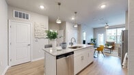 This thoughtfully designed 1-bedroom, 1-bathroom residence offers a functional and stylish single-floor layout. The open-concept kitchen serves as the heart of the home, featuring white cabinetry, granite countertops, stainless steel appliances, and a central island with pendant lighting and bar seating. Light wood-style flooring flows throughout the main living areas, enhancing the bright and airy atmosphere. A dedicated dining area adjacent to the kitchen provides additional space for entertaining. The living room is highlighted by a distinctive sage green accent wall, large windows that invite abundant natural light, and a private door leading to an outdoor view. The bedroom is a comfortable retreat with plush carpeting, large windows offering outdoor views, and a soft blue accent wall that adds a calming touch. The bathroom connects directly to the bedroom and features white cabinetry, granite countertops, a large vanity mirror, and wood-style flooring. A dedicated walk-in closet off the bedroom offers wire shelving for ample storage. The entrance and an additional closet complete this well-rounded layout, making efficient use of every square foot.