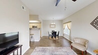 This well-appointed one-bedroom, one-bathroom home in Leesburg, Florida offers a thoughtfully designed single-floor layout that maximizes every square foot. The living room serves as the heart of the home, featuring wood-look flooring, a ceiling fan, and a sliding glass door that floods the space with natural light while providing direct access to an outdoor patio area. Adjacent to the living room, the dining area is defined by a stylish chandelier overhead and a window dressed in warm, layered curtains, creating an inviting setting for meals. The galley-style kitchen is efficiently arranged with light wood cabinetry, ample counter space, a full suite of appliances including a gas range, microwave, and refrigerator, and wood-look flooring that ties seamlessly into the main living areas. A dedicated in-unit laundry room accommodates a full-size washer and dryer with overhead shelving for added storage. The spacious primary bedroom features plush carpet, a ceiling fan, and a bright window with sheer curtains that allow soft natural light to fill the room. The full bathroom is finished with wood-look flooring, a combined tub and shower, a vanity with light stone countertops, and light wood cabinetry. Neutral tones and clean lines throughout give this home a warm, cohesive feel.