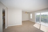 This single-floor residence offers a well-organized layout that balances comfort and functionality throughout. The centerpiece of the living area is a striking full-wall brick fireplace with a gold-framed insert, adding warmth and character to the space. Plush wall-to-wall carpeting extends across the living area, which is bathed in natural light streaming through a large sliding glass door that opens to a private balcony overlooking lush greenery. A ceiling fan overhead provides year-round comfort, while a textured ceiling adds subtle architectural detail throughout the home. The kitchen is efficiently designed with warm oak cabinetry, ample counter space, and white appliances including a dishwasher, range, and refrigerator, all set on easy-care tile flooring. The bedroom is a quiet, carpeted retreat with a dedicated window that invites natural light. Two bathrooms serve the home, each featuring oak vanity cabinetry, a white countertop with an integrated sink, and a large wall mirror. One bathroom includes a shower with a decorative curtain and tile flooring. Neutral wall tones and consistent finishes throughout the home create a cohesive, move-in ready atmosphere that is both practical and inviting.