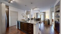 Located at 910 Deerfield Crossing Dr in Alpharetta, GA, this well-appointed 2-bedroom, 3-bathroom residence offers a thoughtfully designed single-floor layout. The open-concept kitchen and living area serves as the heart of the home, featuring rich dark wood cabinetry, stainless steel appliances, a subway tile backsplash, and a central island with a built-in sink and pendant lighting overhead. Hardwood flooring extends throughout the main living areas, complemented by a ceiling fan and large windows that invite natural light into the space. The living area provides a comfortable and versatile setting that flows seamlessly from the kitchen. Both bedrooms are carpeted and generously sized, with large windows offering views of the surrounding greenery. Each bedroom is supported by dedicated closet space — including a spacious walk-in closet with multi-tier rod systems. The bathrooms are finished with large-format tile flooring, dark wood vanities with quartz-style countertops, and one features a full soaking tub with tile surround. The overall ambiance is clean, modern, and cohesive, with a neutral color palette and consistent finishes throughout.