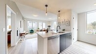 This well-appointed two-bedroom, two-bathroom residence at 100 Hale Ave in White Plains, NY offers a thoughtfully designed single-floor layout. The open-concept kitchen flows seamlessly into the living area, anchored by a peninsula with a white quartz countertop, dark cabinetry, a stainless steel dishwasher, and a matte black sink fixture. Pendant lighting adds a contemporary touch overhead. Light wood-style flooring runs throughout, complementing the neutral palette.

The living room is generously proportioned, bathed in natural light from a wall of windows that frame urban views of White Plains. The spacious primary bedroom features a wall-mounted split AC unit, light-filled windows, and ample room to furnish comfortably. The second bedroom includes a sliding door closet and warm, neutral tones. Both bathrooms are finished in a clean, modern style — one featuring a glass-enclosed shower, stone-tile flooring, a floating dark vanity, and a backlit mirror.

Throughout the residence, a consistent modern aesthetic is maintained with soft gray and white tones, light flooring, and contemporary fixtures, creating a bright, cohesive living environment in the heart of White Plains.