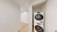 Located on the 16th floor at 351 Marin Blvd in Jersey City's vibrant waterfront district, this one-bedroom, one-bathroom residence offers a well-designed layout with a clean, modern aesthetic throughout. Light hardwood flooring flows seamlessly across the entire unit, complementing the bright white walls and contemporary finishes.

The open-concept kitchen and living area serves as the heart of the home, anchored by a central island with a sleek quartz countertop, undermount sink, and pendant lighting above. The kitchen is fully equipped with stainless steel appliances—including a refrigerator, microwave, and range—set against white subway tile backsplash and taupe cabinetry. Large floor-to-ceiling windows with black frames flood the space with natural light and frame striking views of the Jersey City and New York City skylines.

The bedroom is a quiet, well-proportioned retreat featuring its own oversized window with expansive city and greenery views, continuing the home's connection to the surrounding urban landscape.

The bathroom is finished with large-format neutral floor tiles, a wood-toned vanity with an integrated sink, a mirrored medicine cabinet, and tiled shower walls, offering a clean and functional design.

This high-floor unit combines modern interiors with exceptional urban views, making it a compelling residence in one of Jersey City's most sought-after locations.