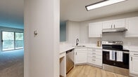Located at 3200 Inglewood Ave S in St. Louis Park, MN, this one-bedroom, one-bathroom unit offers a well-organized and functional single-floor layout. The updated kitchen is a standout feature, equipped with crisp white cabinetry with matte black hardware, light quartz countertops, a corner sink with a black gooseneck faucet, and a full suite of stainless steel appliances including a range, dishwasher, and refrigerator. Light wood-look vinyl plank flooring runs throughout the kitchen, adding warmth and continuity. The combined kitchen and living area provides an open, connected feel with a hallway leading efficiently to the private spaces beyond. The generously sized bedroom features neutral carpet, a window with a lush green outdoor view, and baseboard heating. A dedicated walk-in closet with dual hanging rods and carpet flooring offers excellent storage capacity. The full bathroom is finished with white tile flooring, a white vanity with ample cabinet storage, a large mirror, and matte black fixtures throughout. Neutral tones and clean finishes create a cohesive, move-in-ready aesthetic throughout the entire unit.