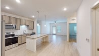 This single-story, 2-bedroom, 2-bathroom residence in Parker, Florida offers a thoughtfully designed open-concept layout with contemporary finishes throughout. The kitchen is a standout feature, equipped with stainless steel appliances including a refrigerator with ice maker, electric range, and microwave. Light wood-tone cabinetry with ample storage, a white subway tile backsplash, and granite countertops complement the space, while a central island with pendant lighting provides additional prep and seating space. The kitchen flows seamlessly into the living area, which features light wood-style flooring and a ceiling fan, creating a bright and airy atmosphere. Natural light enters through windows fitted with blinds, and a door leads to an exterior access point. Both bedrooms are carpeted and equipped with ceiling fans, offering a comfortable retreat. Each bedroom has access to a well-appointed bathroom featuring granite-topped vanities with wood-tone cabinetry, tub-shower combinations, and light wood-style tile flooring. One bathroom includes grab bars for added accessibility. The bedrooms also feature walk-in or standard closets, providing generous storage. Clean white walls and consistent modern finishes unify the entire home.
