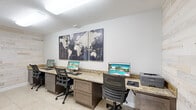 Located at 518 Lake Bridge Ln in Apopka, Florida, this single-room business center offers a thoughtfully designed workspace within a compact footprint. The room is defined by its distinctive whitewashed shiplap accent walls, which lend a clean, modern aesthetic and serve as a warm contrast to the crisp white painted surfaces throughout. Light-toned ceramic tile flooring runs throughout the space, contributing to its bright and polished appearance.

The workstation area features a continuous granite-topped built-in desk in a rich, warm tone, providing generous surface space for multiple users simultaneously. Two ergonomic task chairs accompany the dual computer monitors and a shared printer, making the setup well-equipped for everyday business needs. Dark-stained cabinetry with drawer storage beneath the countertop adds both functionality and a refined visual anchor to the room.

A bold world map canvas art piece displayed prominently above the main workstation serves as a striking decorative focal point. Flush-mounted ceiling lighting ensures consistent illumination throughout. A glazed interior door with a frosted panel connects the space to an adjacent area, while a window introduces natural light and maintains an open feel. The overall ambiance is professional yet inviting, blending practical amenities with contemporary design details.