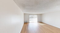 Located at 425-455 E Washington Ave in Escondido, CA, this well-appointed one-bedroom, one-bathroom unit offers a comfortable and functional layout across a single floor. Light-toned hardwood-style flooring runs throughout, creating a warm and cohesive aesthetic in every room.

The living area is open and airy, featuring a textured ceiling, neutral walls, and a sliding glass door fitted with vertical blinds that fills the space with natural light and provides views of the surrounding greenery. A wall-mounted HVAC unit ensures year-round comfort.

The kitchen is efficiently designed with white shaker-style cabinetry, light countertops, a stainless steel sink with gold-tone hardware, and a full-size refrigerator. A ceiling fan with an integrated light fixture adds both function and style to the space.

The spacious primary bedroom receives generous natural light through a large window with exterior views, and continues the consistent hardwood-style flooring found throughout the unit. An adjacent walk-in closet offers ample storage with built-in hanging rods.

The bathroom is clean and well-finished, featuring a white vanity with stone-look countertop, a large mirror with elegant wall-mounted lighting, and a shower/tub combination. The entrance provides a welcoming transition into the overall layout of this thoughtfully designed unit.