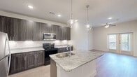 Located at 4909 E Lancaster Ave in Fort Worth, TX, this well-appointed one-bedroom, one-bathroom residence offers a thoughtfully designed single-floor layout with modern finishes throughout. Light wood-style flooring flows seamlessly across every room, creating a cohesive and contemporary aesthetic.

The kitchen is a standout feature, showcasing dark wood cabinetry with brushed silver hardware, granite countertops, a stainless steel refrigerator, built-in microwave, and a black electric range. A central island with a granite surface and single-basin sink serves as a functional focal point, accented by elegant pendant lighting overhead — ideal for meal prep and casual dining.

The living area is bright and airy, with a ceiling fan and glass-panel French doors that invite natural light and provide outdoor access. The bedroom offers a calm retreat with a window framing greenery views, a ceiling fan, and access to a spacious walk-in closet outfitted with multi-level shelving and hanging rods for generous storage.

The bathroom features a granite-topped vanity with an undermount sink, matching cabinetry, a soaking tub, and a large mirror. Natural light filters in through the connected bedroom, enhancing the open feel. Clean white walls and recessed lighting throughout contribute to the unit's bright, polished ambiance.