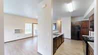 Located at 4130 E 16th Ave in Liberty Lake, WA, this single-floor residence offers 2 bedrooms and 2 bathrooms within a well-organized, functional layout. The open-concept kitchen and living area forms the heart of the home, featuring light wood-style flooring, dark espresso cabinetry, a double-basin sink, and black appliances including a refrigerator, dishwasher, and range. A structural column divides the kitchen from the living room, which receives natural light through large windows overlooking a green outdoor area. The spacious primary bedroom is generously proportioned, with dual windows allowing ample natural light and hard-surface flooring. The second bedroom is finished with plush carpet and a single window with blinds. Both bathrooms feature rich wood-toned vanity cabinetry, light countertops, large mirrors, and hard-surface flooring — one bathroom includes a grab bar for added accessibility. A dedicated closet provides useful storage, and the attached garage with an automatic opener adds everyday convenience. Neutral warm-toned walls, dark wood baseboards, and consistent flooring materials create a cohesive aesthetic throughout the home. The single-floor design ensures easy accessibility and a seamless flow between all living spaces.