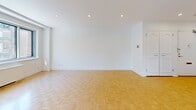 Located at 4555 Avenue Bonavista in the Côte-des-Neiges neighbourhood of Montréal, this well-appointed one-bedroom, two-bathroom unit offers a functional and comfortable single-floor layout. The living room is generously proportioned, featuring classic parquet flooring and a wide picture window that frames views of mature trees and the surrounding neighbourhood, flooding the space with natural light. Recessed lighting complements the bright, white walls throughout, creating a clean and airy ambiance. The kitchen is modern and well-equipped, showcasing white cabinetry, dark countertops, stainless steel appliances, and large-format floor tiles. A peninsula counter provides additional workspace and defines the transition between the kitchen and living areas. The bedroom continues the parquet flooring theme, includes a closet, and benefits from a window with pleasant outdoor views. Both bathrooms are tastefully renovated with large-format grey tiles, floating white vanities, and chrome fixtures. The primary bathroom features a bathtub, while the second offers a glass-enclosed shower. In-unit laundry is also present, adding everyday convenience to this thoughtfully designed Montréal residence.
