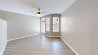 Located at 2120 N Brevard St in Charlotte's NoDa neighborhood, this well-appointed unit offers a thoughtfully designed single-floor layout. The open-concept kitchen and living area serves as the heart of the space, featuring dark espresso cabinetry, granite countertops, a stainless steel appliance suite including a French door refrigerator, electric range, microwave, and dishwasher, complemented by a peninsula with pendant lighting — ideal for both meal prep and casual dining. Light wood-style flooring flows throughout the main living areas, creating a bright and cohesive aesthetic. The living area is bathed in natural light from multiple windows with views of the surrounding community, and a ceiling fan adds both function and comfort. The bathroom is elegantly finished with a dark wood vanity topped with granite, a large mirror, subway tile tub/shower surround, and wood-look tile flooring. The spacious walk-in closet features built-in wire shelving and carpeted flooring, providing ample organized storage. Neutral gray tones on the walls throughout lend the space a clean, modern ambiance well-suited for contemporary living.