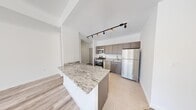 Located at 100 Evergreen Place in East Orange, NJ, this four-bedroom, two-bathroom unit at The Althea offers a well-designed single-floor layout with modern finishes throughout. The open kitchen serves as a central feature, equipped with stainless steel appliances including a gas range, dishwasher, microwave, and refrigerator. Taupe shaker-style cabinetry pairs with granite countertops and a peninsula that provides additional workspace and casual seating. Light-toned tile flooring and track lighting complete the kitchen's contemporary aesthetic.

The living room is bright and spacious, benefiting from large floor-to-ceiling windows that invite substantial natural light and offer views of the surrounding neighborhood. Light wood-tone laminate flooring extends throughout the living areas and bedrooms, creating a cohesive look. The generously sized primary bedroom includes its own windows and wall-unit climate control. The additional bedrooms are well-proportioned with clean white walls and ample natural light.

Both bathrooms feature marble-style tile flooring in crisp white tones, contributing a clean, refined finish. The overall design of the unit emphasizes a neutral, modern palette, making it a functional and well-appointed space.