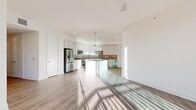 Located at 468 Quay Commons in the heart of Sarasota, FL, this well-appointed three-bedroom, two-bathroom residence offers a thoughtfully designed single-floor layout with a clean, contemporary aesthetic. Light wood-style flooring and crisp white walls flow throughout, creating a bright and cohesive atmosphere.

The open-concept kitchen is a standout feature, showcasing tall white shaker cabinetry, a neutral tile backsplash, stainless steel appliances including a refrigerator, dishwasher, and built-in microwave, as well as a beverage cooler. A central island with pendant lighting above provides additional prep space and a natural gathering point.

The main living area opens directly to a private balcony through large sliding glass doors, flooding the room with natural light and offering views of the Sarasota skyline and surrounding buildings. A ceiling fan adds comfort to the space.

The spacious primary bedroom comfortably accommodates generous furniture arrangements, and the bathrooms are finished with clean tile flooring, glass-enclosed showers with bench seating, and understated vanities. Two dedicated closets, including a walk-in with built-in shelving, provide ample storage. A central hallway connects all rooms efficiently, completing this well-organized and modern residence.