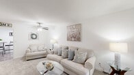 Located at 4981 Hunt Club Rd in Winston-Salem, NC, this well-appointed single-floor, one-bedroom, one-bathroom home offers a thoughtfully organized layout with a warm, neutral aesthetic throughout. The living room serves as the heart of the space, featuring soft carpeting, a ceiling fan with light fixture, and bright white walls that create an airy, welcoming atmosphere. A front-facing window with blue curtains allows natural light to filter in, enhancing the open feel of the room. The kitchen is outfitted with white cabinetry, dark countertops, a dishwasher, and wood-look flooring, offering a clean and functional cooking area with ample cabinet storage. The spacious primary bedroom accommodates a full bedroom suite comfortably, complete with plush carpeting, a window with sheer curtains for natural light, and generous wall space. The full bathroom includes a tub-shower combination with a clean white surround. A dedicated laundry area houses a full-size washer and dryer with overhead wire shelving for added storage convenience. Two closets further enhance the storage capacity of this efficiently designed home, while a connecting hallway ties all rooms together seamlessly for easy navigation throughout the space.