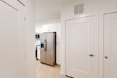 Located at Pelham Ave SW in Huntsville, Alabama, this single-floor unit offers a clean, modern aesthetic defined by bright white walls, light wood-look flooring, and a cohesive contemporary design throughout. The open-concept kitchen serves as a central highlight, outfitted with white shaker-style cabinetry extending to the ceiling, light quartz countertops, a subway tile backsplash, and a full suite of stainless steel appliances including a side-by-side refrigerator with water and ice dispenser, an electric range, over-the-range microwave, and a dishwasher. A deep undermount sink with a brushed gold faucet is positioned on the kitchen peninsula, which is accented by a pendant light and offers views toward the living area and a window that draws in natural light. The living area is open and versatile, featuring the same light flooring and crisp white walls that create a bright, airy atmosphere. The bathroom includes a glass-enclosed walk-in shower with tile surround and a backlit mirror, complemented by light flooring that maintains the unit's consistent palette. A dedicated closet provides practical storage, and clean-profile interior doors with modern hardware complete the polished look throughout the space.