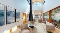 Located at 7555 E Warren Dr in Denver, Colorado, this Clubhouse and Business Center is a thoughtfully designed community facility that seamlessly blends social and professional spaces. The single-floor layout offers a generous footprint that accommodates a variety of functions without feeling cluttered.

The centerpiece of the living room lounge is a striking suspended conical fireplace that anchors the soaring vaulted ceiling, clad in warm wood paneling and flanked by expansive clerestory windows that flood the space with natural light. Comfortable neutral-toned seating is arranged throughout, creating inviting areas for relaxation and conversation. Large artwork adorns the white walls, adding a curated, gallery-like character to the space.

Moving through the open-plan interior, the gathering area features high-top communal tables with bar-height seating, a wall-mounted flat-screen TV set against a slatted wood accent wall, and industrial-style pendant lighting overhead. Polished concrete floors and large exterior-facing windows connect the interior to the outdoors. A fully equipped kitchen area supports events and casual use.

A glass-walled fitness area is visible from the lounge, maintaining visual openness while defining distinct zones. The dedicated business center office provides a quiet, focused workspace with built-in desks, multiple computer workstations, and natural light from exterior windows, all accented by vibrant artwork.