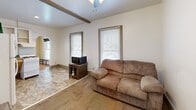 Located at 1002 Emerson Ave in South Bend, Indiana, this two-bedroom, one-bathroom home offers a practical and efficiently laid-out single-floor plan. The living area greets you with a ceiling fan, distinctive exposed wood ceiling beams, and multiple windows fitted with blinds that allow for natural light throughout the day. Mixed flooring — including tile and carpet — defines distinct zones within the open living, dining, and kitchen space, which is connected via a charming arched doorway. A hallway with a rustic barn-style sliding door leads to the rest of the home. The primary bedroom features warm hardwood floors, a ceiling fan, and a large window overlooking the neighborhood, offering ample natural light. The second bedroom is finished with matching hardwood flooring and a window with blinds, providing a clean and versatile space. The bathroom stands out with bold reddish-brown walls, large-format tile flooring, a walk-in tiled shower, and a frosted window for privacy. The overall layout of the home is straightforward and functional, making efficient use of every room. This property presents a cozy and manageable living space ideal for those seeking a low-maintenance home in South Bend.