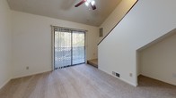 Located at 4300 Neil Rd in Reno, Nevada, this two-story residence offers a well-organized layout with a variety of functional spaces across both levels. The main living area is immediately welcoming, highlighted by soaring vaulted ceilings, a ceiling fan, and a sliding glass door that opens to an outdoor space, filling the room with natural light and views of surrounding greenery. A staircase leads to the upper level, reinforcing the sense of vertical space throughout.

The kitchen is open and efficiently designed, featuring white cabinetry, light countertops, stainless steel appliances including a refrigerator and dishwasher, an electric range, and wood-style flooring. It connects seamlessly to the living area, making the space feel cohesive and practical.

Bathrooms are clean and functional, each featuring wide vanities with ample cabinet storage, large mirrors, and light countertops. One bathroom includes a separate water closet with wood-style flooring, while another offers a tub-shower combination.

The bedrooms are carpeted and generously proportioned, with windows that bring in natural light. Closet access is visible in the upper-level bedroom. Throughout the home, neutral tones, plush carpet in living and sleeping areas, and wood-style flooring in wet areas create a consistent, understated aesthetic suited for comfortable everyday living.