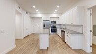 Located at 1925 W North Temple in Salt Lake City, UT, this modern 4-bedroom, 2-bathroom unit offers a well-designed single-floor layout. The heart of the home is a bright, open-concept kitchen, dining, and living area featuring crisp white shaker cabinetry, a white subway tile backsplash, quartz countertops, a central kitchen island, and a full suite of stainless steel appliances including a refrigerator, range, microwave, and dishwasher. Recessed lighting and light wood-look flooring run throughout, creating a clean and contemporary aesthetic. Large windows in the living area and bedrooms invite natural light and frame views of the surrounding Salt Lake City skyline. The four bedrooms are thoughtfully sized, with the primary bedroom offering notable space, and several rooms include built-in shelving or closet access. Five closets provide generous storage throughout the unit. The two bathrooms are finished in a clean, all-white palette with tub-shower combinations and chrome fixtures. Additional conveniences include a dedicated laundry area, a balcony, and a hallway connecting the private quarters. The overall ambiance is bright, modern, and move-in ready.