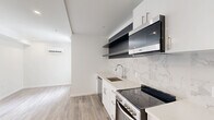 Located at 1201 Vine St in Philadelphia's vibrant Chinatown/Callowhill neighborhood, this thoughtfully designed studio maximizes every inch of its compact footprint. The open-plan living, dining, and kitchen area is anchored by light wood-look flooring and crisp white walls, creating a bright, airy atmosphere. A large window allows natural light to fill the living space, which also features a wall-mounted mini-split HVAC unit for year-round comfort and recessed lighting throughout.

The kitchen is a standout, outfitted with sleek white cabinetry, open dark-toned floating shelves, a marble-look tile backsplash, quartz-style countertops, and a full suite of stainless steel appliances including a dishwasher, electric range, microwave, and refrigerator. The bathroom continues the upscale aesthetic with floor-to-ceiling marble-look tile and a glass-enclosed walk-in shower featuring a rain showerhead and handheld fixture. In-unit laundry is provided via a stacked washer and dryer conveniently tucked in a dedicated hallway alcove. A utility closet with an electrical panel and an additional closet round out the functional layout of this efficiently designed urban residence.