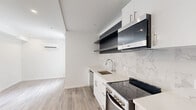 Located at 1201 Vine St in Philadelphia's vibrant Chinatown/Callowhill neighborhood, this thoughtfully designed studio maximizes every inch of its compact footprint. The open-plan living, dining, and kitchen area is anchored by light wood-look flooring and crisp white walls, creating a bright, airy atmosphere. A large window allows natural light to fill the living space, which also features a wall-mounted mini-split HVAC unit for year-round comfort and recessed lighting throughout.

The kitchen is a standout, outfitted with sleek white cabinetry, open dark-toned floating shelves, a marble-look tile backsplash, quartz-style countertops, and a full suite of stainless steel appliances including a dishwasher, electric range, microwave, and refrigerator. The bathroom continues the upscale aesthetic with floor-to-ceiling marble-look tile and a glass-enclosed walk-in shower featuring a rain showerhead and handheld fixture. In-unit laundry is provided via a stacked washer and dryer conveniently tucked in a dedicated hallway alcove. A utility closet with an electrical panel and an additional closet round out the functional layout of this efficiently designed urban residence.