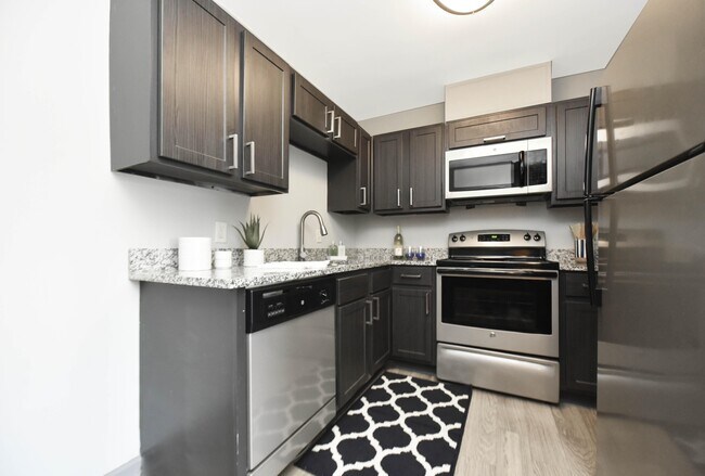 Cocina con encimeras de granito, electrodomésticos de acero inoxidable y gabinetes modernos. - Overton Brentwood