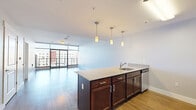 Located at 221 Harborside Dr in Schenectady, NY, this well-appointed one-bedroom, one-bathroom unit offers a thoughtfully designed open floor plan. The combined kitchen and living area serves as the heart of the home, featuring light hardwood-style flooring and striking floor-to-ceiling windows that flood the space with natural light and frame sweeping outdoor views of the surrounding waterfront area. A central kitchen island with granite countertops and a built-in sink anchors the space, complemented by rich dark-wood cabinetry, a tile backsplash, and a full suite of stainless steel appliances including a refrigerator, electric range, and microwave. Pendant lighting above the island adds a modern touch. The bedroom is carpeted for comfort and includes a closet alcove and a window with outdoor views. The bathroom is clean and functional, featuring a tub/shower combination, tile flooring, and a vanity with granite countertops. Additional spaces include a dedicated laundry area, a utility room, and two closets, providing ample storage throughout. The overall aesthetic is contemporary and bright, with neutral tones and modern finishes creating a cohesive and inviting atmosphere.
