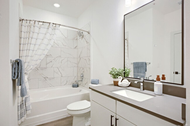 Marble-look tile and a deep bathtub elevate the everyday. Enjoy the BH-A1 floor plan's clean, modern bathroom at Garrett Harvest Junction West, Longmont, CO. - Garrett Harvest Junction West
