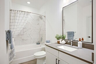 Marble-look tile and a deep bathtub elevate the everyday. Enjoy the BH-A1 floor plan's clean, modern bathroom at Garrett Harvest Junction West, Longmont, CO. - Garrett Harvest Junction West