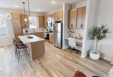 This contemporary Argenta Townhome offers a spacious 1240 square feet of living area spread across three floors. The layout includes 2 bedrooms, 3 bathrooms, and a variety of functional spaces. The ground floor spans 150 square feet, while the first and second floors offer 570 and 520 square feet respectively.

The heart of the home is an open-concept living, dining, and kitchen area. The kitchen boasts modern light wood cabinetry, stainless steel appliances, and a central island with seating. Large windows throughout flood the space with natural light, creating an airy atmosphere. The living room features a comfortable orange sofa, perfect for relaxation or entertaining.

Both bedrooms are generously sized, with the primary bedroom measuring 140 square feet. They are equipped with large windows and plush carpeting for comfort. The bathrooms are sleek and modern, featuring contemporary fixtures and finishes.

The townhome includes practical amenities such as multiple closets for storage, including a walk-in closet with built-in organizers. Five staircases connect the different levels, ensuring easy navigation throughout the home.

The interior design is characterized by a neutral color palette, hardwood flooring in common areas, and tasteful decorative elements that create a cohesive, modern aesthetic. This Argenta Townhome model offers a perfect blend of style, comfort, and functionality for contemporary urban living.