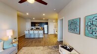 This single-story, 2-bedroom, 2-bathroom residence offers a thoughtfully designed open-concept layout with wood-look flooring throughout. The living area is bright and welcoming, featuring a ceiling fan, a sectional seating area, and French doors that invite natural light while providing outdoor access.

The kitchen is a functional centerpiece, equipped with dark espresso cabinetry, stainless steel appliances including a refrigerator, range, and microwave, along with granite countertops and a breakfast bar with seating for multiple guests. A dedicated in-unit laundry area is conveniently accessible from the kitchen.

The primary bedroom is spacious, with natural light from large windows, a ceiling fan, and direct access to its own bathroom. The second bedroom also features a ceiling fan and window, making it a comfortable and versatile space.

Both bathrooms mirror each other in design, each offering dark vanity cabinetry with granite countertops, a tub-shower combination, and open built-in shelving for added storage. The consistent use of wood-look flooring and neutral tones throughout creates a cohesive, modern aesthetic across the entire residence.