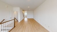 Located at 25 Pennsylvania Ave in Perth Amboy, NJ, this multi-level townhouse spans three floors and offers 2 bedrooms and 3 full bathrooms. The entry level features an attached garage with a standard roll-up door, concrete flooring, interior access doors, and additional storage space — providing both convenience and utility.

The main living floor is generously proportioned and bathed in natural light, thanks to large windows with classic mullion detailing. Light wood-toned flooring runs throughout, complementing the crisp white walls and recessed ceiling lights. The open-plan kitchen and living area flows seamlessly, with the kitchen featuring a window overlooking the outdoors and access to a staircase flanked by a wood-and-spindle railing. A hallway connects the key areas of this floor.

The upper floor houses both bedrooms, including a spacious primary bedroom with dual closet access and a window admitting natural light. The second bedroom is equally well-appointed, also featuring a closet. All three bathrooms are finished cleanly, with light wood-tone flooring, modern vanities with gray countertops, warm wood cabinetry, and a tiled shower-tub combination. Staircases connect all three levels, providing easy circulation throughout this well-designed, move-in-ready home.