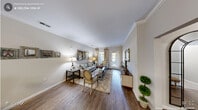 This well-appointed 2-bedroom, 2-bathroom residence in Raleigh, NC offers a thoughtfully designed single-level layout with elegant finishes throughout. The open-concept living area features hardwood-style flooring, crown molding, and neutral toned walls that create a bright, cohesive atmosphere. A glass-paneled door floods the living room with natural light, complementing the welcoming ambiance. The kitchen is equipped with dark espresso cabinetry, dark granite countertops, stainless steel appliances including a refrigerator and range, and a double-basin undermount sink at the center island, which opens directly to the living space. The dedicated dining area accommodates a round table beneath a contemporary chandelier, with crown molding continuing the refined aesthetic. The spacious primary bedroom features a tray ceiling with ceiling fan, plush carpeting, and an en-suite bathroom with a dark granite vanity and framed mirror. The second bedroom offers comfortable proportions with a closet and carpet flooring. The second bathroom mirrors the same upscale finishes, featuring tile flooring, a dark-cabinetry vanity, and granite countertop. A hallway and closet round out this well-organized floor plan, making this Raleigh residence both functional and stylish.