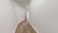 Located at 5477 200 Street in Langley, BC, this well-appointed 2-bedroom, 2-bathroom unit offers a thoughtfully designed layout across a single floor. The contemporary kitchen serves as a standout feature, showcasing wood-grain cabinetry with a high-gloss finish, white quartz countertops, a subway tile backsplash, stainless steel appliances, and a central island with an undermount sink — all illuminated by track lighting and a pendant fixture. Durable hardwood-style flooring runs throughout the main living areas, adding warmth to the open feel of the space. The living area is bright and airy, with a large window framing lush green tree views. Both bedrooms are carpeted for comfort, and each benefits from natural light and outdoor access via sliding glass doors leading to a private balcony with pleasant greenery views. One bedroom also features dual windows and a built-in closet for added storage. The two bathrooms are finished with tile flooring, dark countertops, and white cabinetry — one includes a full tub and shower with decorative tile accents. A hallway and additional closet round out the functional layout of this clean, modern residence.