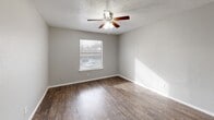 Located at 1839 S Glenbrook Dr in Garland, TX, this single-story home offers 2 bedrooms and 2 bathrooms within a practical and well-organized layout. The open living, dining, and kitchen area serves as the heart of the home, featuring dark hardwood-style flooring, neutral gray walls, and a textured ceiling throughout. A distinctive pass-through counter with a dark granite surface connects the kitchen to the living space, adding functionality and a sense of openness. The kitchen also includes a pantry for additional storage. Both bedrooms are carpeted and equipped with ceiling fans and windows that allow natural light to fill the rooms. The spacious primary bedroom features a walk-in closet with built-in shelving. The second bedroom also benefits from a ceiling fan and closet access. The two bathrooms mirror each other in style, each featuring a white vanity with under-cabinet storage, a lighted mirror, and hardwood-style flooring. One bathroom includes additional built-in shelving for extra storage. With four closets total distributed throughout the home, storage is plentiful. A hallway connects the private sleeping quarters to the shared living spaces, creating a clear and functional separation within the floor plan.
