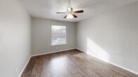 Located at 1839 S Glenbrook Dr in Garland, TX, this single-story home offers 2 bedrooms and 2 bathrooms within a practical and well-organized layout. The open living, dining, and kitchen area serves as the heart of the home, featuring dark hardwood-style flooring, neutral gray walls, and a textured ceiling throughout. A distinctive pass-through counter with a dark granite surface connects the kitchen to the living space, adding functionality and a sense of openness. The kitchen also includes a pantry for additional storage. Both bedrooms are carpeted and equipped with ceiling fans and windows that allow natural light to fill the rooms. The spacious primary bedroom features a walk-in closet with built-in shelving. The second bedroom also benefits from a ceiling fan and closet access. The two bathrooms mirror each other in style, each featuring a white vanity with under-cabinet storage, a lighted mirror, and hardwood-style flooring. One bathroom includes additional built-in shelving for extra storage. With four closets total distributed throughout the home, storage is plentiful. A hallway connects the private sleeping quarters to the shared living spaces, creating a clear and functional separation within the floor plan.