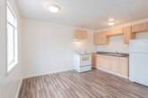 Located at 911 Randolph St. in Portsmouth, Virginia, this single-floor unit offers a practical and well-organized layout designed for comfortable everyday living. The open living area is finished with warm wood-look laminate flooring that extends throughout the main spaces, creating a clean and cohesive aesthetic. A window unit provides climate control, and natural light filters in through a front-facing window, brightening the room. The kitchen is efficiently arranged in an L-shaped configuration, featuring light wood cabinetry, dark countertops, a white electric range, a refrigerator, and a sink — providing all the essentials in a compact, functional footprint. The kitchen flows naturally from the living space, making the area feel connected and open. The bedroom is carpeted for comfort and includes two separate closets, offering generous storage space. A ceiling light fixture adds a classic touch to the room. The bathroom is finished with warm beige floor-to-ceiling wall tiles surrounding a full soaking tub and shower combination, complemented by chrome fixtures for a clean, polished look. Throughout the unit, white walls and neutral finishes create a bright, move-in-ready environment suited to a variety of personal styles.
