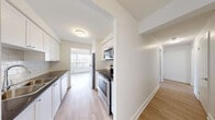Located at 560 Proudfoot Lane in London, Ontario, this well-appointed two-bedroom, two-bathroom unit offers a clean, modern living environment across a single floor. Light-toned hardwood flooring runs throughout the main living areas and bedrooms, creating a bright and cohesive aesthetic complemented by crisp white walls and white trim.

The spacious living room is a standout feature, boasting a wide bank of floor-to-ceiling windows that flood the space with natural light and frame sweeping views of the surrounding greenery and cityscape. The galley-style kitchen is efficiently designed with white cabinetry, dark countertops, a classic subway tile backsplash, and a full suite of stainless steel appliances including a refrigerator, stove, and built-in microwave.

The generously sized primary bedroom benefits from its own window with an outdoor view, while the second bedroom offers a similarly bright and open feel. Both rooms feature the same warm hardwood flooring found throughout the unit. Two bathrooms serve the space: one features sleek grey tile flooring with a white vanity and a tub surround, while the second presents a clean, minimalist design with a modern chrome faucet and large mirror. A dedicated utility room completes the layout, adding practical storage and functional convenience to this well-organized home.