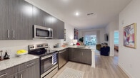 Located at 680 Hamilton Ave SE in Atlanta's Grant Park neighborhood, this single-floor residence combines contemporary design with functional living. The open-concept layout seamlessly connects the kitchen, dining, and living areas, creating a cohesive and airy atmosphere throughout.

The kitchen is outfitted with dark wood-grain cabinetry extending to the ceiling, stainless steel appliances including a range, microwave, dishwasher, and refrigerator, and granite-look countertops. The peninsula provides additional prep space and serves as a natural divider between the kitchen and living area.

Light wood-style flooring runs through the main living spaces, enhancing the sense of openness. The living room features a sliding glass door that opens to a private balcony, allowing natural light to flow in and providing outdoor views. Bold, colorful artwork adorns the walls, adding vibrancy to the neutral palette.

The bedroom is a calm retreat with plush carpeting, a ceiling fan, large windows with views to the exterior, and ample wall space accented by decorative artwork. The bathroom features granite-look countertops, dark cabinetry consistent with the kitchen, and direct access to a walk-in closet with built-in hanging storage. The entry foyer provides a clean transition into the home with light flooring and a welcoming layout.